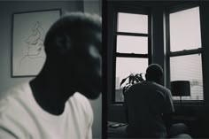 a man sitting in front of a window next to a plant