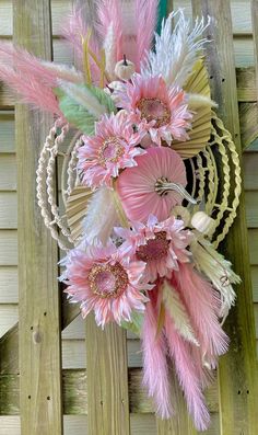 pink and white flowers are in a vase on a wooden table next to a fence