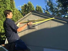 a man is working on the roof of his house with a large pair of scissors