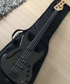 a black bass guitar case sitting on top of a wooden floor next to a rug