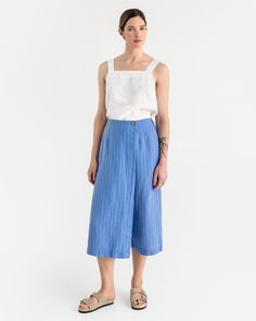 These unique linen culotte pants BUSAN in blue stripes blend style and comfort seamlessly. They come with an elastic back waist for comfort, front seams for a tailored look, and a discreet zipper closure for ease of wear. The skirt element is enhanced with a coconut button, adding a fashionable detail, while side pockets provide convenient utility. Details: * Loose fit * 3/4 length * Elasticated waist at the back  * Pants feature a secret zipper closure * Skirt part finished with a coconut butto Spring Wide Leg Pants With Vertical Stripes, Wide Leg Ankle-length Pants With Vertical Stripes For Spring, Spring Wide Leg Pants With Vertical Stripes, Ankle-length, Spring Ankle-length Wide Leg Pants With Vertical Stripes, Chic Striped Linen Bottoms, Relaxed Fit Striped Wide Leg Pants For Spring, Striped Linen Wide-leg Pants, Striped Wide-leg Linen Pants, Spring Cotton Wide Leg Pants With Vertical Stripes