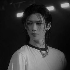 black and white photograph of a woman with dark hair wearing a necklace in a darkened room