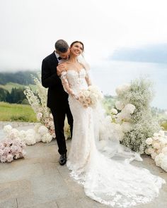 a bride and groom standing in front of flowers