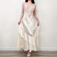 a woman in a white dress is standing against a wall and posing for the camera