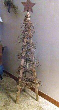 a christmas tree made out of branches and other items on the floor in front of a wall