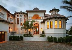 a large white house with lots of windows on the front and side of it at dusk