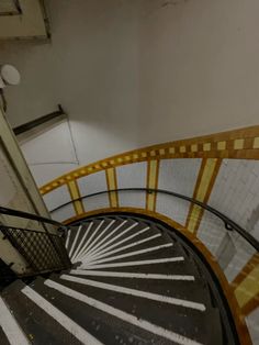 a spiral staircase in an old building with yellow and white stripes on the railings