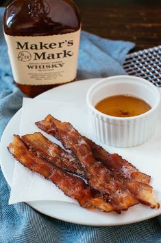 bacon on a plate next to a bottle of whiskey