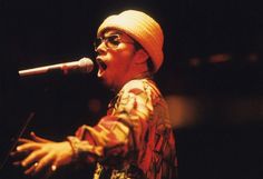 a man singing into a microphone while wearing glasses and a beanie on his head