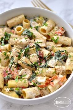 a white bowl filled with pasta and spinach on top of a marble countertop