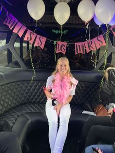 a woman sitting on the back of a car with balloons and streamers hanging from it