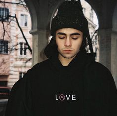 a young man wearing a black hoodie with the word love on it and a cat hat