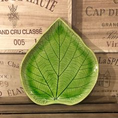 a green leaf shaped plate sitting on top of a wooden table