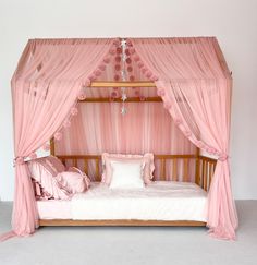 a pink canopy bed with curtains and pillows