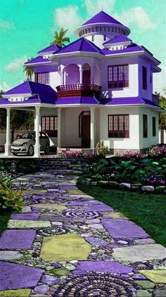 a purple and white house is shown in the daytime time with flowers on the lawn