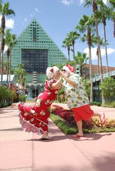 two women dancing in front of a building with palm trees