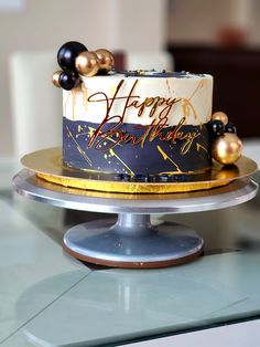 a birthday cake sitting on top of a metal platter with gold and black decorations