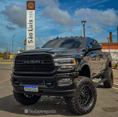 a large black truck parked in front of a sign