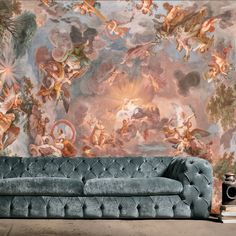 a blue couch sitting in front of a wall with paintings on it's walls