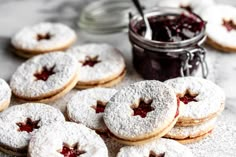 cookies with jam and powdered sugar are arranged on a table