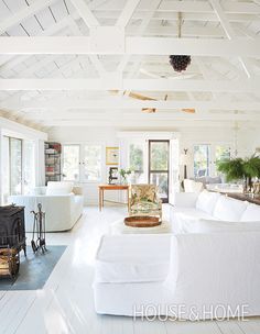 a living room filled with white furniture and lots of windows