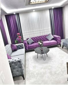 a living room with purple and grey furniture in the center, along with white rugs