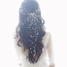 the back of a woman's head with white pearls on her hair and veil