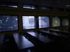 an empty classroom with tables and chairs in the dark