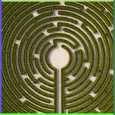 a large circular maze in the middle of a field with grass growing through it and an arrow pointing to the center