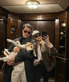 a man and woman taking a selfie with their dogs