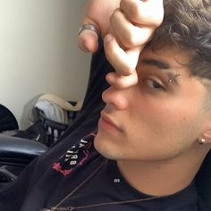 a close up of a person wearing a black shirt and holding his hand to his head