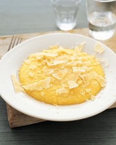 a white plate topped with food on top of a wooden table next to two glasses