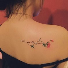 the back of a woman's shoulder with a tattoo that reads, roses are blooming