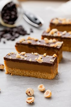 three pieces of cake sitting on top of a counter next to some nuts and chocolate