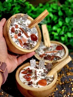 two small wooden bowls filled with food on top of a table next to green plants