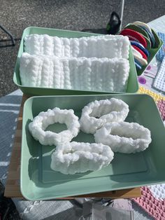 two green trays filled with white yarn on top of a table next to each other