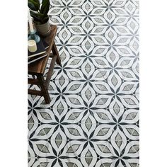 a black and white tile floor with geometric designs on it, next to a plant