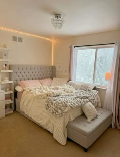 a bedroom with a large bed and a window in it's corner, next to a book shelf