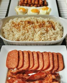 there is rice, meat and eggs on the table with other foods in the background