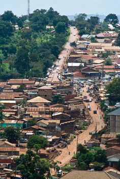 an aerial view of a city with lots of houses and trees on the hillside side