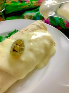 a close up of a plate of food with cheese and sauce on it next to a glass of milk