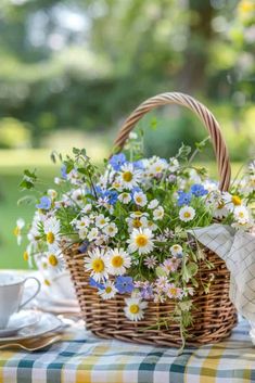 a basket filled with flowers sitting on top of a table next to a cup and saucer