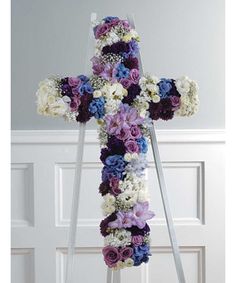 a cross made out of flowers sitting in front of a door