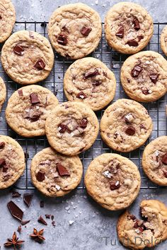 chocolate chip cookies on a cooling rack with sea salt and star anise scattered around them