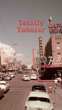 an old time photo of cars driving down the street in front of a neon sign