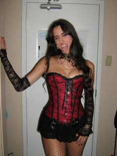 a woman in a corset and fishnet stockings poses for the camera with her tongue out