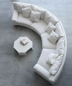 a white couch sitting on top of a cement floor next to a table with books