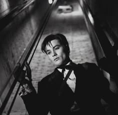 a man in tuxedo and bow tie standing on an escalator looking at the camera