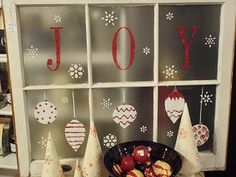 some apples are sitting in a bowl on a table next to christmas decorations and a window