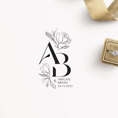 a wedding ring sits on top of a white table next to a box with a gold ribbon tied around it